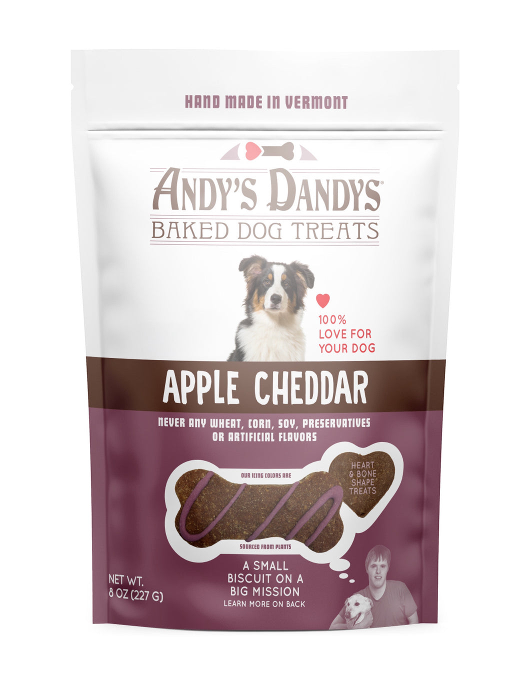 Front of white and purple pouch of tasty Andy's Dandys Apple Cheddar flavor mini bone shaped baked dog biscuits drizzled with purple yogurt icing