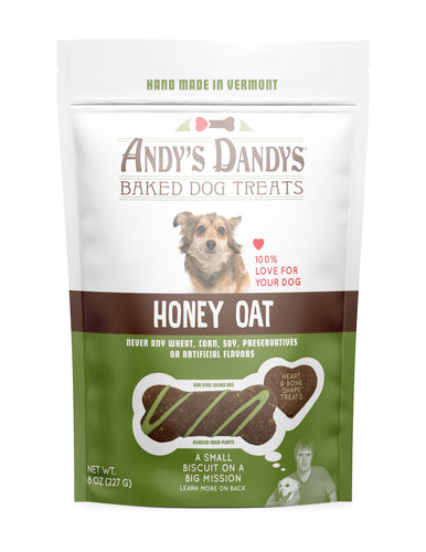 Front of white and green pouch of tasty Andy’s Dandys Honey Oat flavor mini bone and heart shaped baked dog biscuits drizzled with green yogurt icing