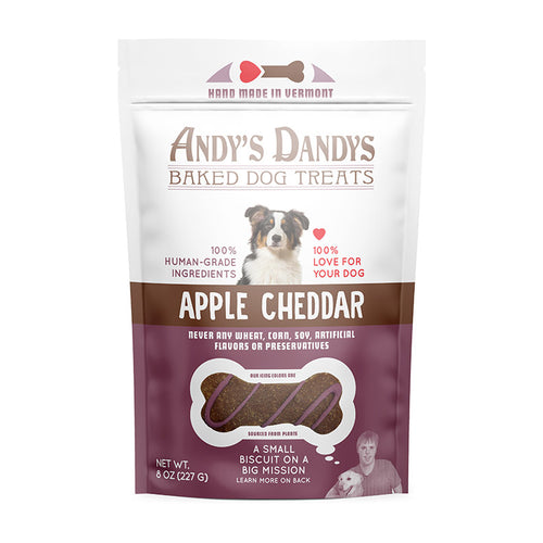 Front of white and purple pouch of tasty Andy's Dandys Apple Cheddar flavor mini bone shaped baked dog biscuits drizzled with purple yogurt icing