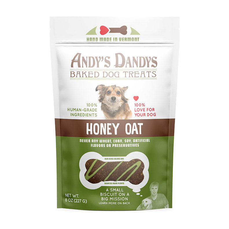 Front of white and green pouch of tasty Andy’s Dandys Honey Oat flavor mini bone and heart shaped baked dog biscuits drizzled with green yogurt icing